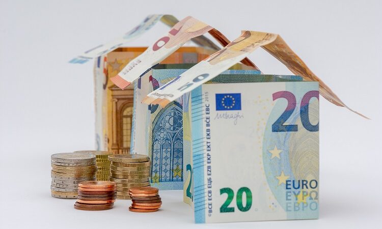 Trois maisons faites en billets de 10, 20, et 50 euros, avec quelques pièces de monnaie